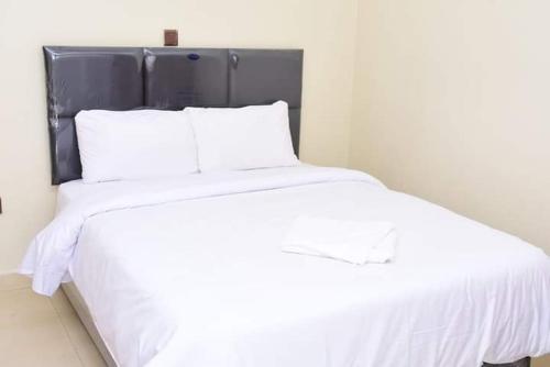 Cama blanca con sábanas y almohadas blancas en Sagada Resort Lamuria en Nyeri