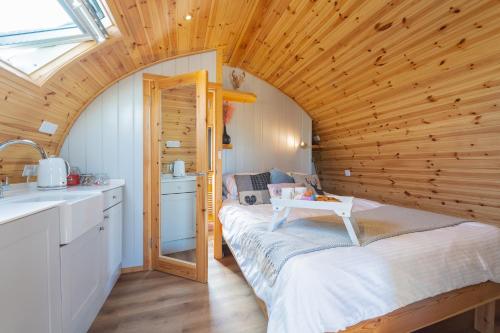 The Stag Pod Farm Stay with Hot Tub Sleeps 2 Ayrshire Rural Retreats في Galston: غرفة صغيرة مع سرير في سقف خشبي