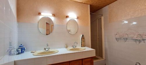 une salle de bain avec deux lavabos et deux miroirs dans l'établissement Villa individuelle de plain pied, au calme, à La Flotte