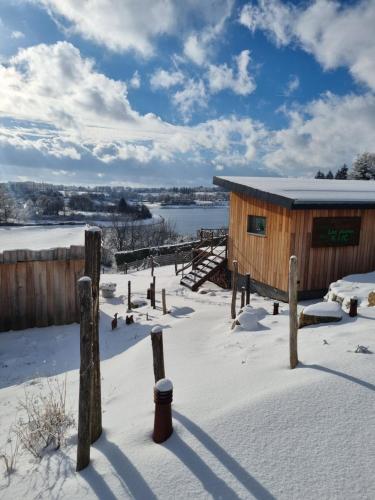 una cabina in legno nella neve con un lago di LAC ABANE AU LAC a Butgenbach