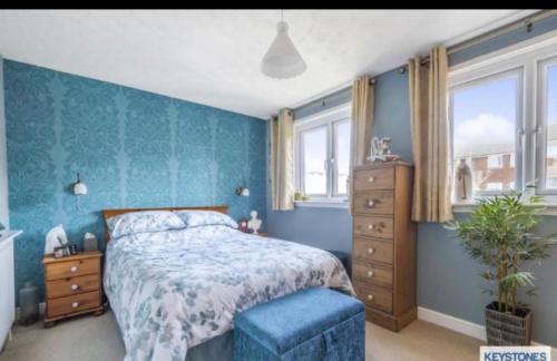 1 dormitorio con cama y pared azul en A Perfect Two Bedroom House for a Family Stay, en Havering atte Bower