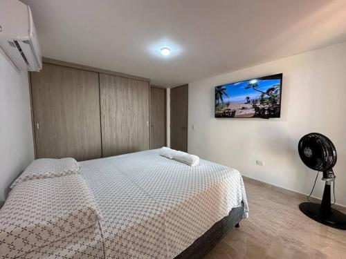 a bedroom with a white bed and a fan at Apartamento Victoria in Puerto Colombia