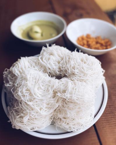 a plate of noodles on a table with bowls of soup at Private Pool Cabanas AC - Angam Villas Hikkaduwa in Hikkaduwa