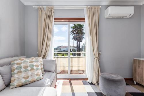 a living room with a couch and a large window at FURADOURO - Vista dos Pinhais - apart 2 quartos a 100 metros da praia do Furadouro in Ovar