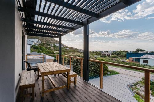 a deck with a wooden table and bench on a balcony at Prinia on Peak in Pringle Bay in Pringle Bay