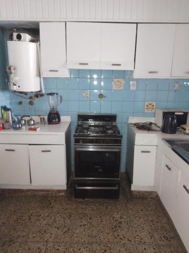 uma cozinha com um fogão e armários brancos em Casa Diego em Olivos