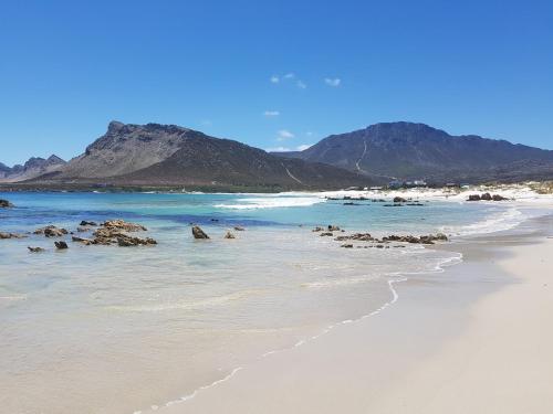 a beach with rocks and the ocean and mountains at Prinia on Peak in Pringle Bay in Pringle Bay