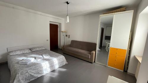 a bedroom with a bed and a couch and a mirror at La Piazzetta, il centro di Biella in Biella