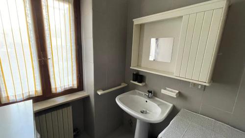 a white bathroom with a sink and a mirror at La Piazzetta, il centro di Biella in Biella
