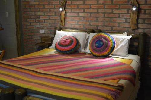 a bed with colorful blankets and pillows on it at Hotel Rustico Cerro Del Valle in San Agustín de Valle Fértil