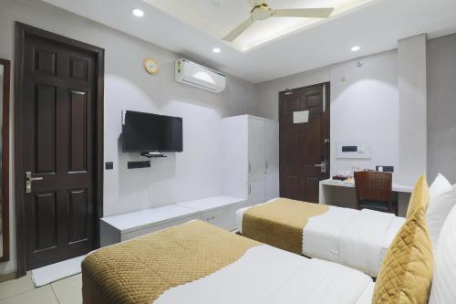 a bedroom with two beds and a tv on the wall at Cosy Grand, Chanakyapuri by The Cosy Hotels in New Delhi