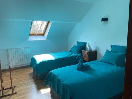 ein blaues Zimmer mit 2 Betten und einem Fenster in der Unterkunft Les Maisons des Halles in Cerisy-la-Forêt