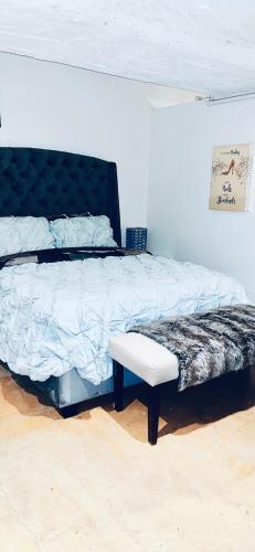 a bedroom with a bed with a black headboard and a bench at Huge Downtown LA Loft with Rooftop Pool & Jacuzzi in Los Angeles