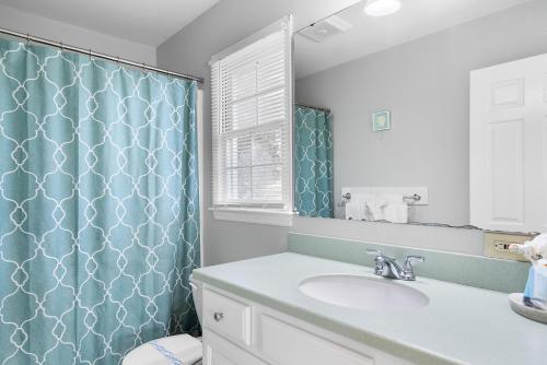 een badkamer met een wastafel en een blauw douchegordijn bij 600 Steps Second Row in North Litchfield Beach