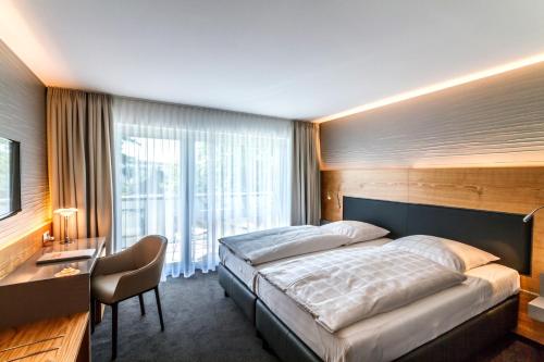 Schlafzimmer mit einem Bett, einem Schreibtisch und einem Fenster in der Unterkunft Hotel Villa Elben Lörrach bei Basel in Lörrach