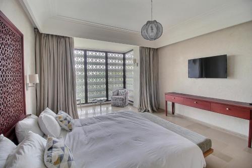 - une chambre avec un grand lit et une télévision à écran plat dans l'établissement Villa de luxe Kasbah Amazigh, à Marrakech