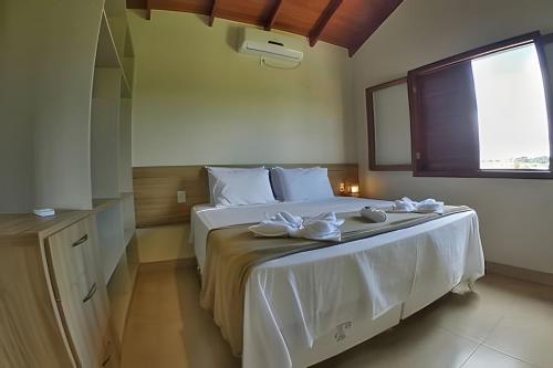 um quarto com uma cama com lençóis brancos e uma janela em Canto do Paraíso - Aluguel para Temporada em Alto Paraíso de Goiás
