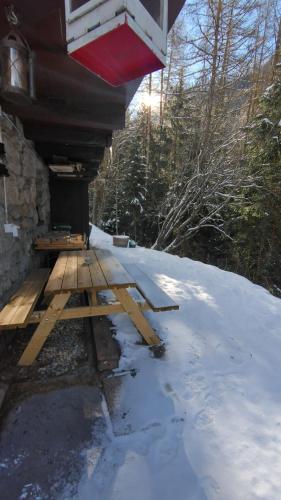a picnic table in the snow next to a house at Petit chalet rustique et bucolique in Bovernier