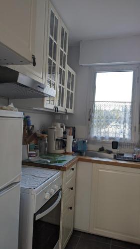 une cuisine avec des armoires blanches et une fenêtre dans l'établissement Le Pouliguen - T1 bis - 5mn à pied de la plage - linge non fourni, au Pouliguen