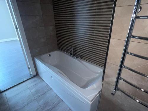 a white bath tub in a bathroom with a window at Spacious 3 bedroom with sea view in Baku