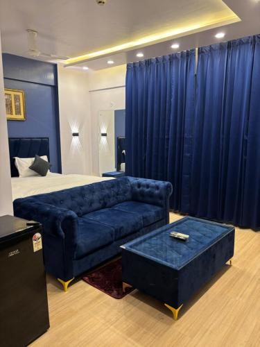 a bedroom with a couch and a bed with blue curtains at The Royal Residency Suites,Lucknow Gomti Nagar in Lucknow
