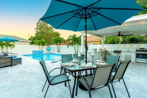 a table and chairs with an umbrella on a patio at Lux Backyard/Heated Pool/Everglades/Speedway/Keys! in Miami