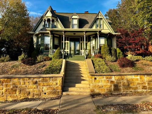 a large green house with a stone wall at MacFie House in Cape Girardeau