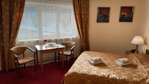 a room with a bed and a table and a window at Geneva Hotel in Ternopil