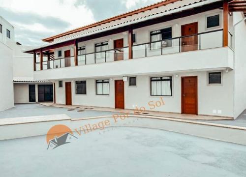 a large white house with a pool in front of it at Arraial do Cabo Village Pôr Do Sol in Arraial do Cabo