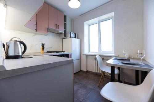 uma cozinha com um frigorífico branco e uma mesa com cadeiras em Квартири метро Дарниця світло завжди є em Kiev