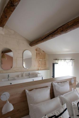 La salle de bains est pourvue d'un lavabo et d'un lit avec des oreillers blancs. dans l'établissement MAISON V AU COEUR DU VILLAGE Alpilles, à Maussane-les-Alpilles