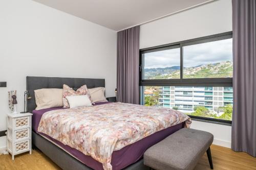 een slaapkamer met een bed en een groot raam bij SkyView Penthouse Apartment by MHM in Funchal