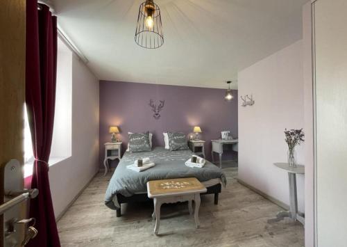 1 dormitorio con cama y pared púrpura en La Cigaliere, en Bézenet