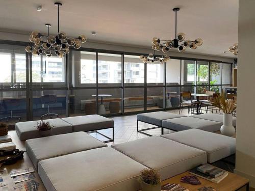 a large room with white couches and tables and windows at Apt. inteiro recém-reformado - Jabaquara in São Paulo