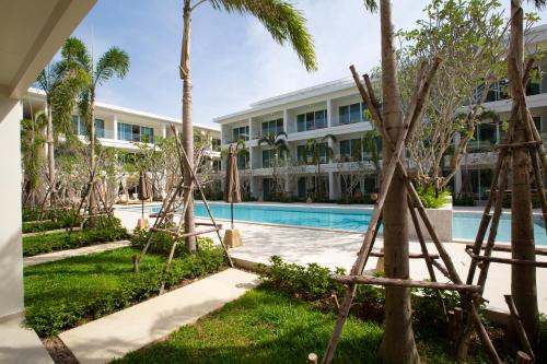 un complejo con piscina y palmeras en Niranapa Boutique Resort, en Kata Beach