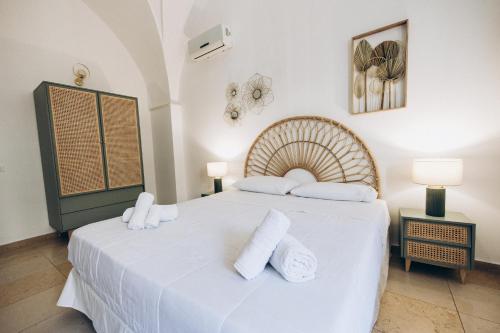 una camera da letto con un letto con lenzuola e asciugamani bianchi di Dalila Apulian Rental Rooms a Pulsano