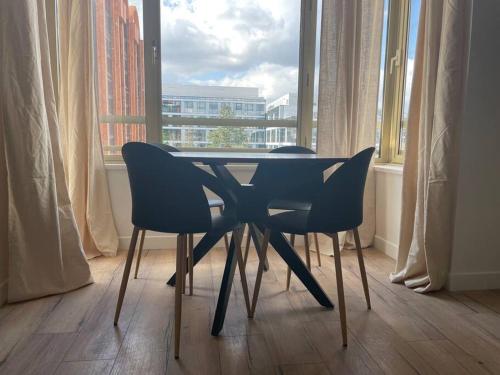 une table et des chaises dans une pièce avec une fenêtre dans l'établissement Le Monochrome - Aux portes de Paris - 327B, à Levallois-Perret