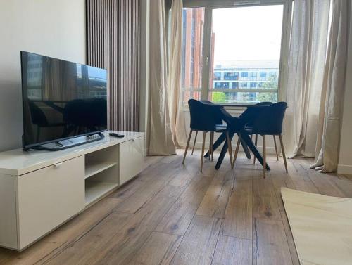 Il comprend un salon doté d'une table et d'une télévision à écran plat. dans l'établissement Le Monochrome - Aux portes de Paris - 327B, à Levallois-Perret