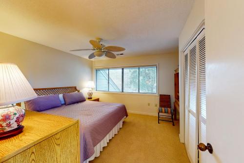 a bedroom with a bed with a ceiling fan and a window at Turnberry Village 258 in Hilton Head Island