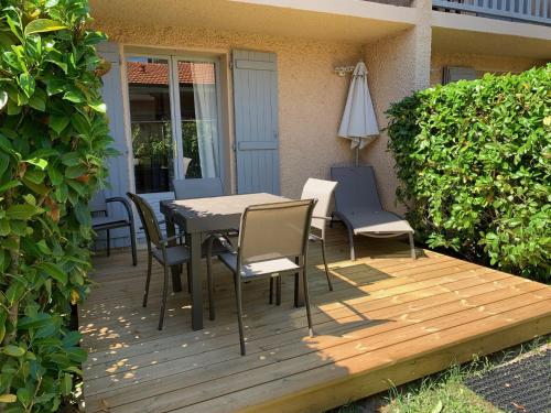 a wooden deck with a table and chairs and an umbrella at LOGIS HOTELS - Hôtel et Restaurant L'Océana in Lanton