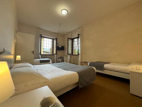 a bedroom with two beds and a television and two windows at Monastero SS. Annunziata in Todi