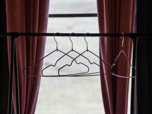 a metal hanger in front of a window with red curtains at Focus Point Drakhtik - Rose Cabin in Drakhtik