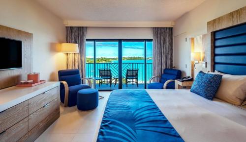 a hotel room with a bed and a view of the ocean at Grotto Bay Beach Resort in Tuckerʼs Town
