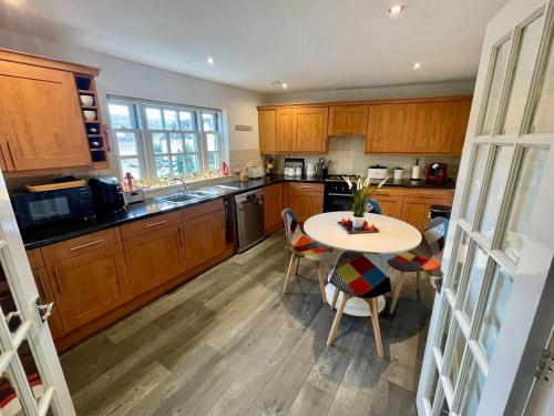 a kitchen with wooden cabinets and a table and chairs at The Gorge Getaway - Deluxe 3-Bedroom Apartment in Cheddar