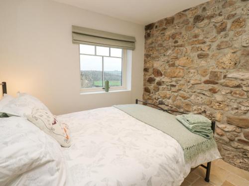 Un dormitorio con una pared de piedra y una cama en Sutton Newbold Cottage en Trimdon Grange