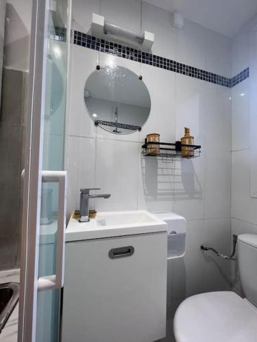 uma casa de banho branca com um lavatório e um WC em Studio a deux pas de Paris em Levallois-Perret