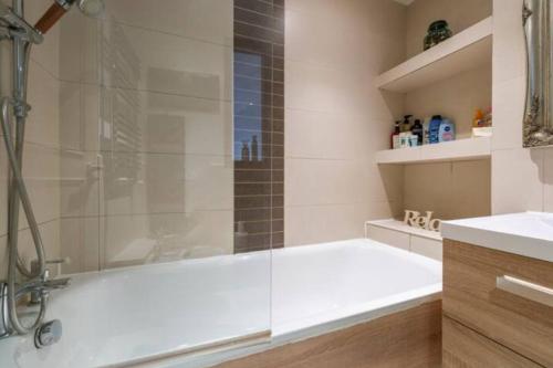 a bathroom with a tub and a glass shower at Super Central beautiful 3 Bedroom in London