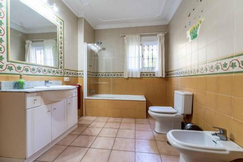 y baño con 2 aseos, bañera y lavamanos. en Villa Exotica, en Nerja