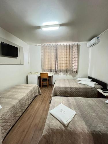 a hotel room with two beds and a television at Regente Hotel in Pato Branco