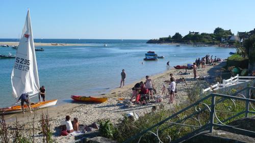 - un groupe de personnes sur une plage avec un voilier dans l'établissement Appartement vue sur mer, à Bénodet